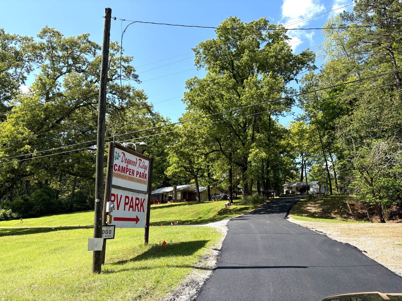Dogwood Ridge RV Park entrance sign with fresh paved road and oak tree canopy